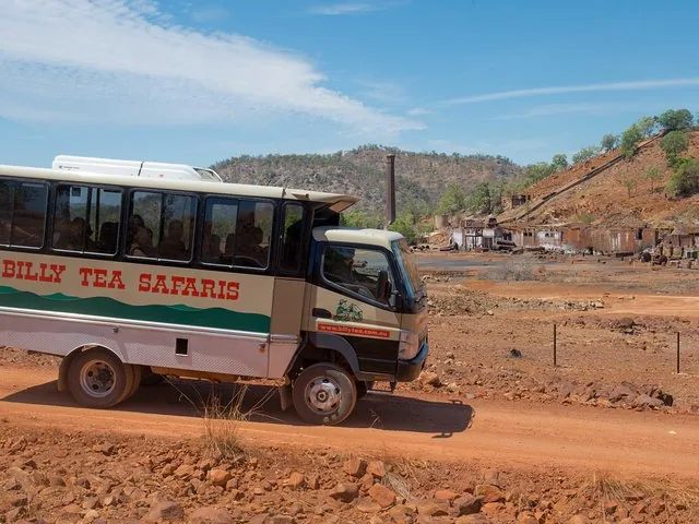 Ein Tourbus von Billy Tea Safaris fährt auf einer Schotterstraße in der Nähe eines Industriegebiets.
