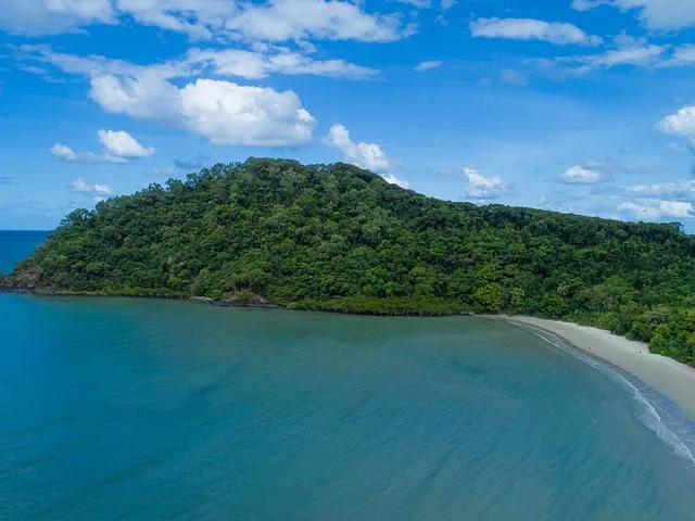 Eine Luftaufnahme einer bewaldeten Insel mit Sandstrand und blauem Wasser.